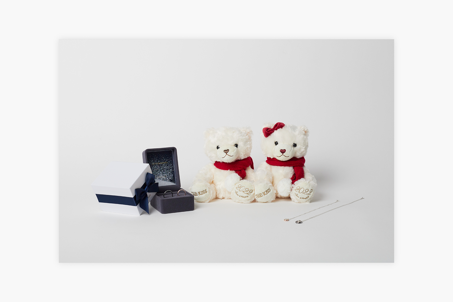 ギフトボックスに入ったアクセサリーと赤いマフラーをした2匹の白いクマ